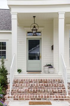 a white house with brick steps leading up to the front door and entryway area