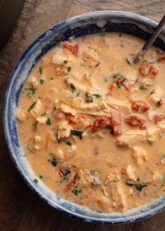 a blue bowl filled with soup on top of a wooden table next to a spoon