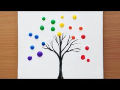 an art project made out of colored pom poms on white paper with a tree