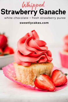 a strawberry cupcake with pink frosting and fresh strawberries on the side, in front of a bowl of strawberries