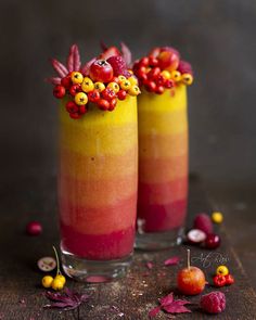 two glasses filled with fruit on top of a wooden table