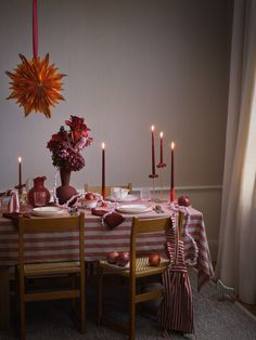 a dining room table is set with red and white striped cloths, candles, and flowers