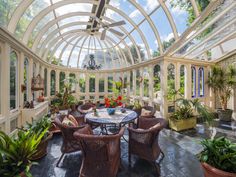 a room filled with lots of furniture and plants inside of a glass walled ceilinged area