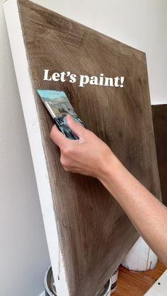 a person is painting the side of a piece of wood that says let's paint