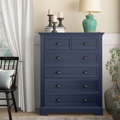 a blue chest of drawers sitting next to a window