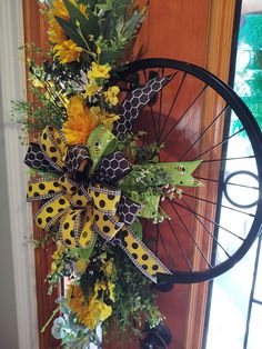 a bicycle wheel decorated with sunflowers and greenery on the front door porch