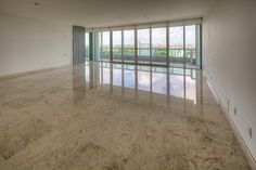 an empty living room with large windows and marble flooring in front of the sliding glass doors