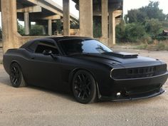 a black sports car parked in front of an overpass