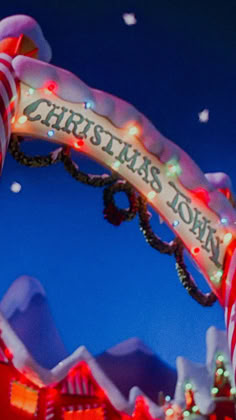 a merry christmas town sign with lights and candy canes on it's side