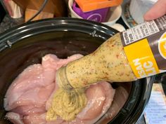 someone is pouring mustard into the meat in the slow cooker