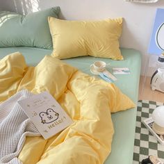 a bed with yellow sheets and pillows on top of it next to a table lamp