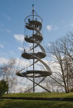 a tall metal spiral staircase on top of a lush green field