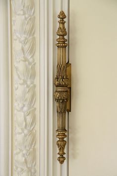 an ornate gold door handle on a white wall