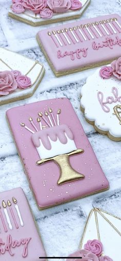 decorated cookies with pink icing and gold trimmings on a white tablecloth