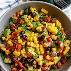 a white bowl filled with corn, black beans, avocado and cilantro