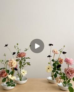 three vases filled with different types of flowers on top of a wooden table next to a white wall