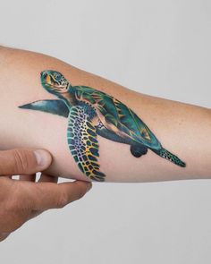 a woman's arm with a tattoo of a turtle on the inside of it