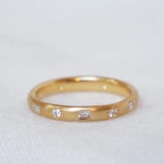 a yellow gold wedding band with three diamonds on it, sitting on a white cloth