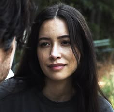 a close up of a person wearing a black shirt with trees in the back ground