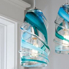 two glass lights hanging from the ceiling in a room with white trimmings and blue accents