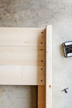 a wooden bed frame with nails and screws on the floor next to an open book