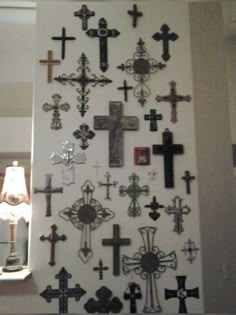 a wall with many crosses on it and a lamp in the corner next to it