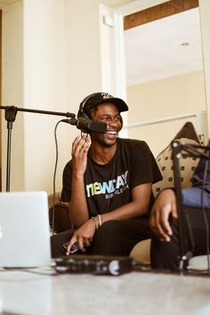 a man sitting in front of a laptop computer on top of a table next to a microphone