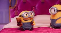 two minion characters sitting on top of a bed in front of a pink headboard