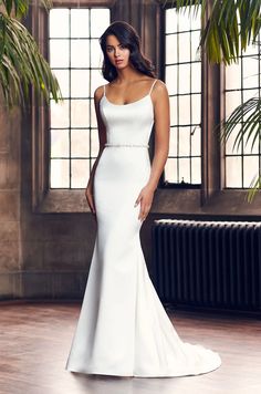 a woman in a white wedding dress posing for the camera with her hands on her hips