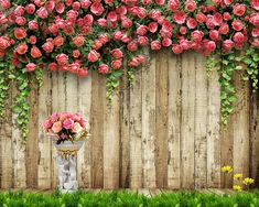 a vase filled with lots of pink flowers next to a wooden fence covered in vines