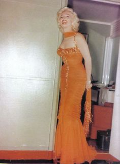 a woman in an orange dress standing next to a door