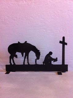 a silhouette of a man kneeling down next to a horse and a person with a crucifix