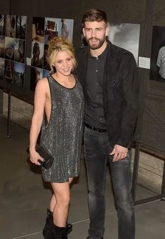 a man and woman standing next to each other in front of pictures on the wall