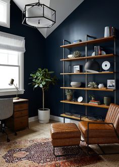 a living room with blue walls and leather chairs in front of a book shelf filled with books