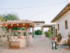 an outdoor wedding venue with lights strung over the entrance and seating area for people to sit on