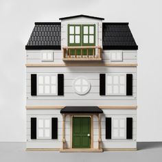 a model house with green doors and windows on the top floor, in front of a white background