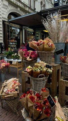 several baskets filled with flowers sitting on top of a wooden table in front of a store