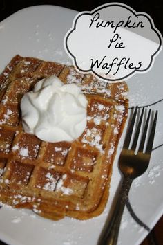 a white plate topped with waffles covered in powdered sugar and whipped cream