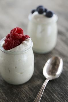 yogurt with raspberries and blueberries in a small glass jar next to a spoon