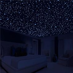 a bedroom with blue stars on the ceiling and white furniture in front of it at night