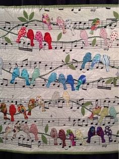 a quilted wall hanging with birds and music notes on it's sides,