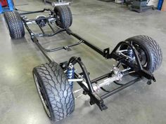 the front wheels and suspensions of a vehicle in a garage with other vehicles behind them