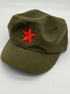 an army green hat with a red star on it's visor, sitting on a white surface