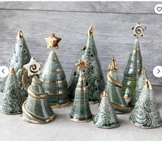 small ceramic christmas trees are lined up on the table