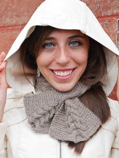 a woman wearing a white jacket with a hood on her head and smiling at the camera