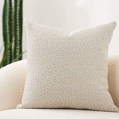 a white pillow sitting on top of a couch next to a potted plant