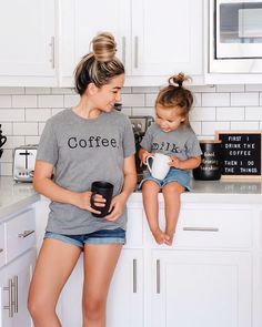 a woman and her daughter sitting on the kitchen counter with coffee mugs in their hands