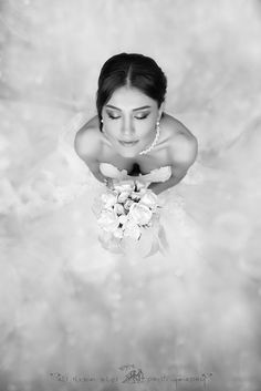 black and white photograph of a bride holding her bouquet in front of the camera, taken from above