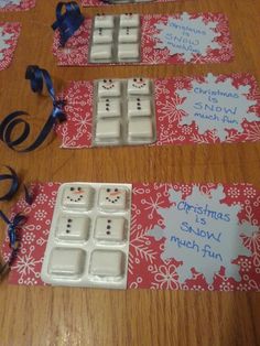 three snowman themed placemats on a table with blue ribbon and decorations around them