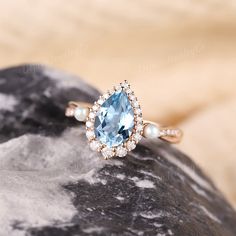 an engagement ring with a blue topaz surrounded by pearls and diamonds on a rock